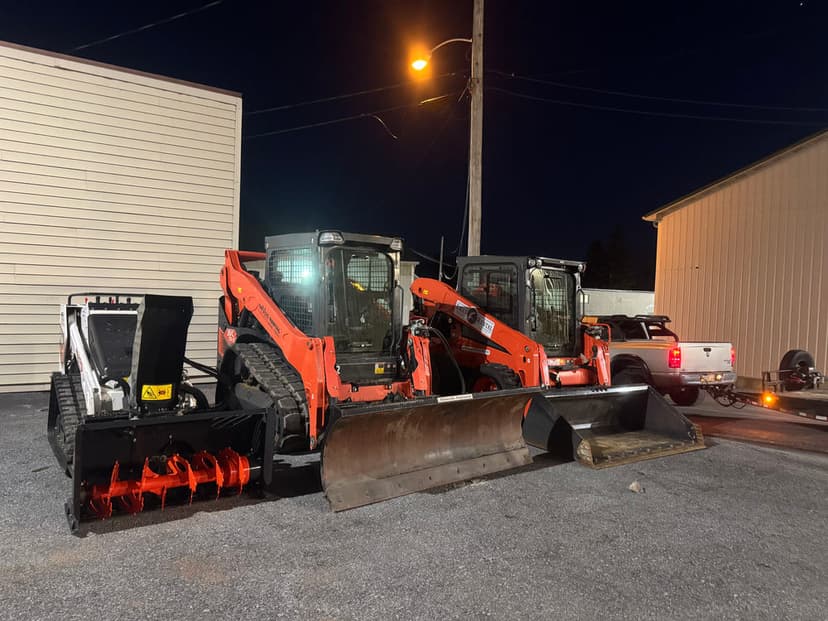 Bobcat skid steers with attachments at night, showcasing heavy machinery and equipment.