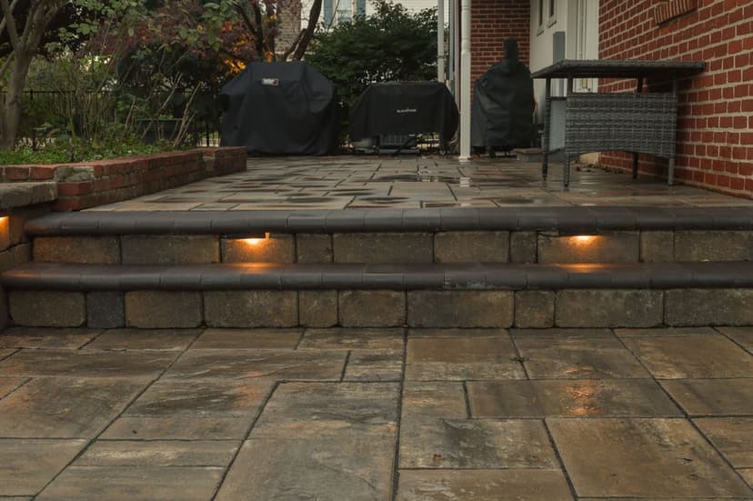 Patio steps with stone finish, illuminated by built-in lighting, surrounded by outdoor furniture.