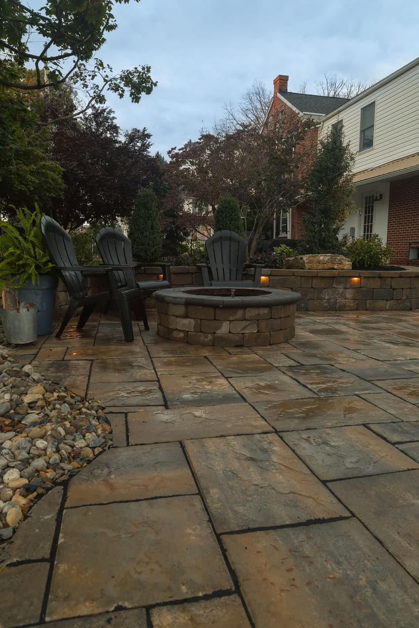 Cozy outdoor seating area with Adirondack chairs and a stone fire pit on a patio.