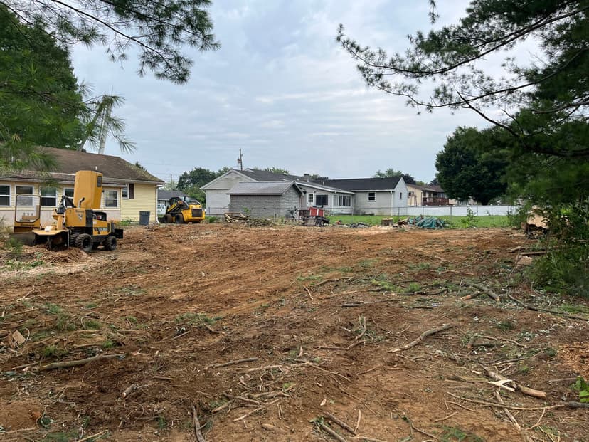 Cleared land with construction equipment and surrounding houses in a suburban area.